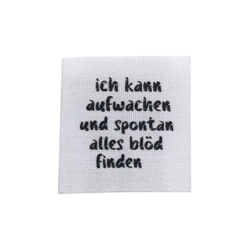 Baumwolllabel mit Aufdruck "ich kann aufwachen und spontan alles blöd finden" in schwarz auf weißem Hintergrund