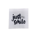 Baumwolllabel mit Aufdruck "just smile" in schwarz auf weißem Hintergrund