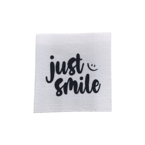 Baumwolllabel mit Aufdruck "just smile" in schwarz auf weißem Hintergrund