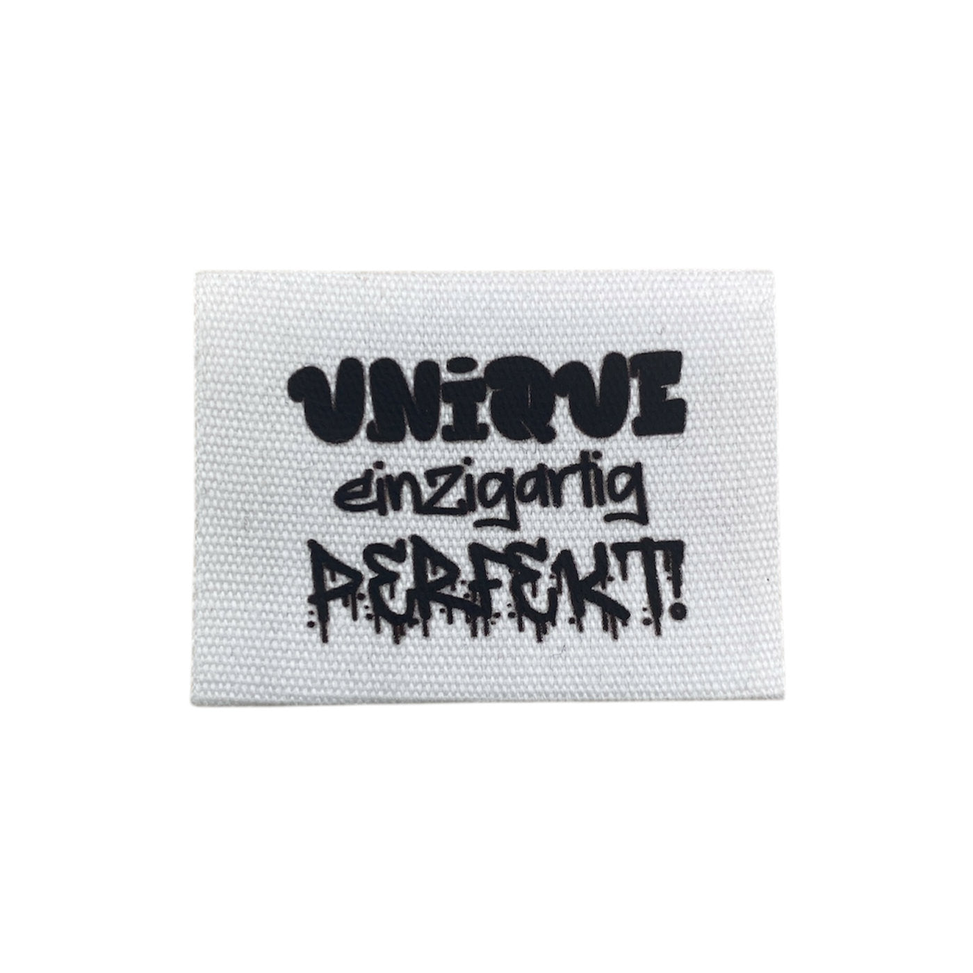 Baumwolllabel mit Aufdruck "unique einzigartig perfekt!" in schwarz auf weißem Hintergrund